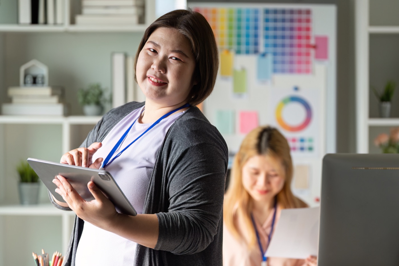 School leader smiling while holding a tablet in an office